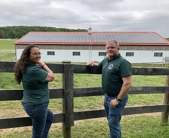 The owners of Gentle Giant Horse Rescue stand in Front of their Arena With Solar Panels.