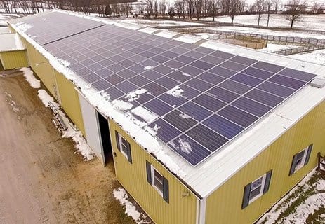 Photovoltaic panels on the roof with snow, with a snow shovel in